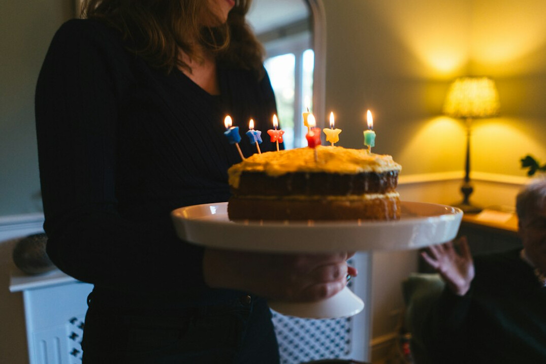 Senior woman celebrating her birthday with cake and friends